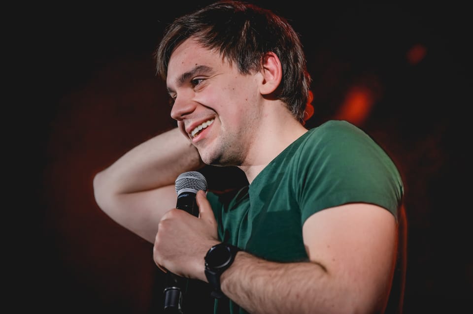 Sebastian Rejent na scenie z mikrofonem, uśmiechnięty